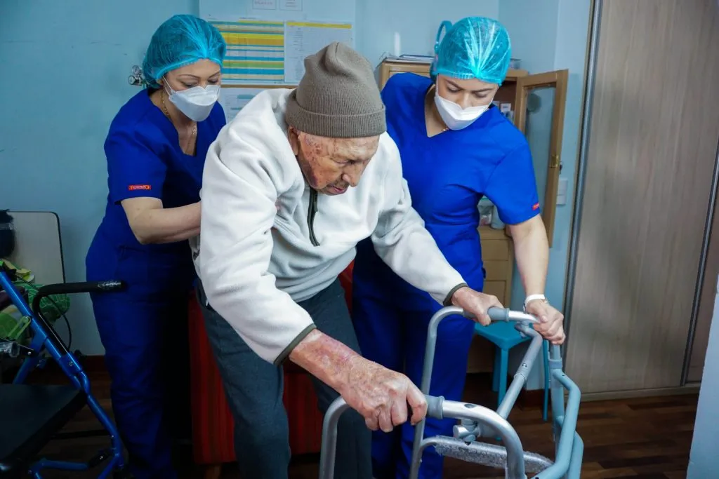 Adulto mayor dependiente recibiendo cuidados de profesionales